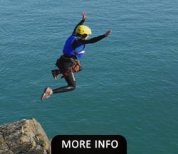 Woman jumping of a cliff while Coasteering North Wales