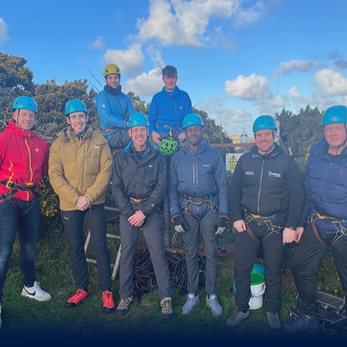 Eight men standing for a group photo after a successful abseiling adventure